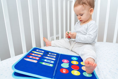 Boy using calculator while sitting on bed at home