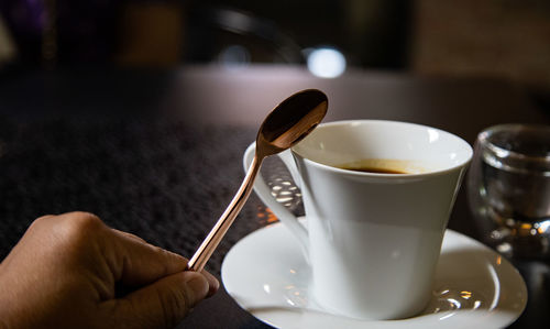 Cropped hand holding coffee on table