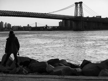 Rear view of silhouette person in front of williamsburg bridge over east river