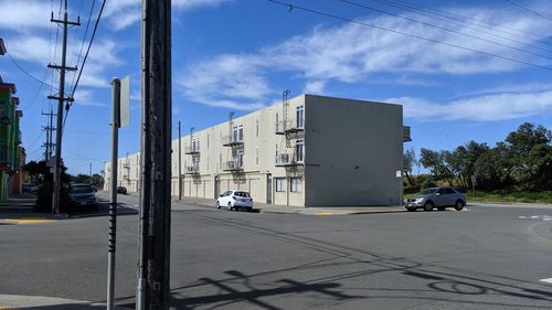 Cars on road by buildings against sky in city