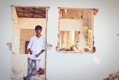 Portrait of young man standing against wall