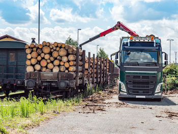 Big truck with crane arm loading wood logs train. cranes at warehouse logs are unloaded from truck