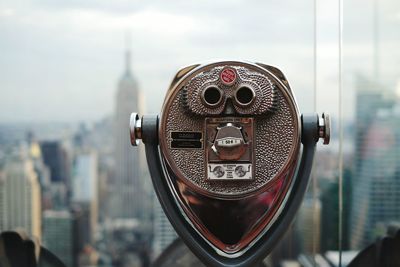 Close-up of coin-operated binoculars against empire state building