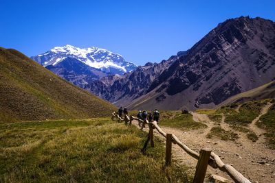 People walking on snowcapped mountain against clear sky