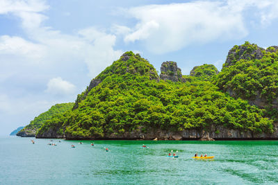 People on boats in sea against sky