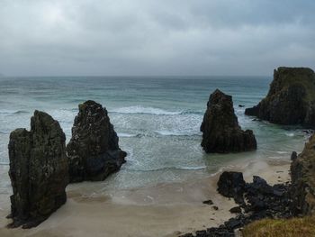 Rock formation on beach against sky