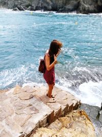 Full length of woman on rock in sea