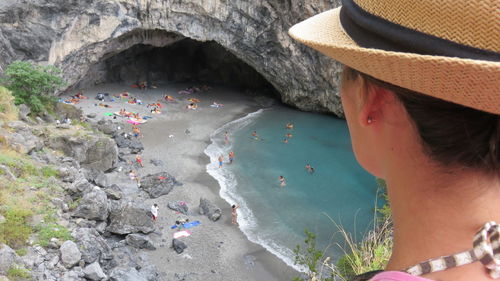 Side view of woman looking towards people at beach