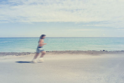 Blurred motion of person on beach against sky