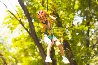 Low angle view of young woman jumping against trees