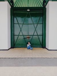 Full length of woman sitting on building