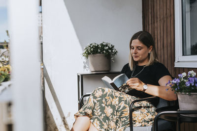 Smiling woman reading book on balcony