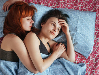 Lesbian woman with girlfriend lying on bed at home