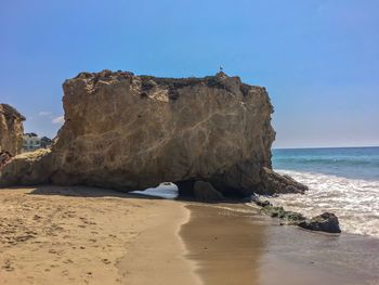 Rock formations on beach against clear sky