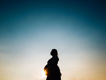 Low angle view of people against clear sky at sunset