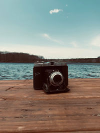 Close-up of camera on lake against sky