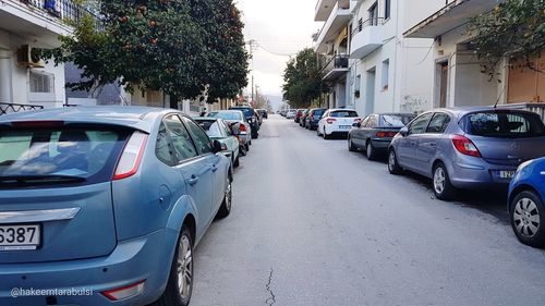 Cars parked on road amidst buildings in city