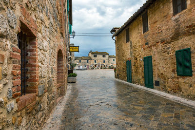 Walkway amidst houses against sky