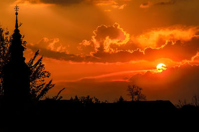 Low angle view of silhouette trees against orange sky