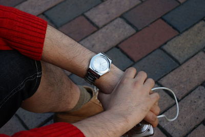 Low section of man holding camera on footpath