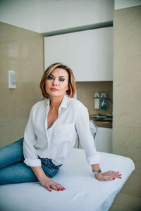 Portrait of young woman sitting on sofa at home