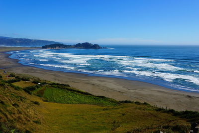 Scenic view of beach against clear blue sky