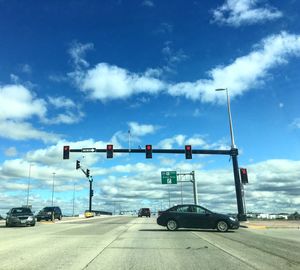 Vehicles on road against cloudy sky