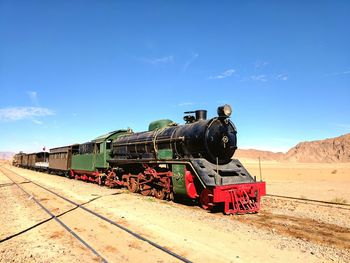 Train on railroad track in desert against sky