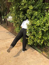 Side view of man standing on footpath amidst plants