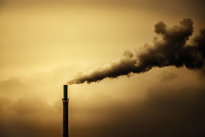 Smoke emitting from chimney against sky