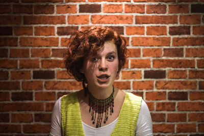 Portrait of young woman against brick wall