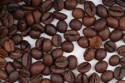 Coffee beans are scattered on a white table. photo of freshly roasted coffee close-up of high