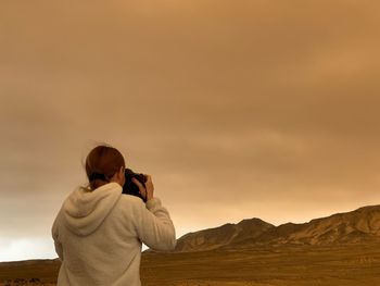 Rear view of woman photographing against sky