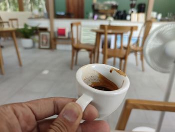 Close-up of hand holding coffee cup on table