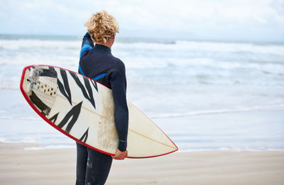 Rear view of woman with arms outstretched standing at beach