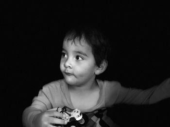 Portrait of cute boy against black background