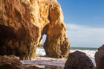 Rock formation on beach against sky