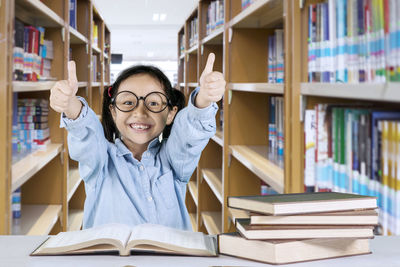 Portrait of smiling girl showing thumbs up in library