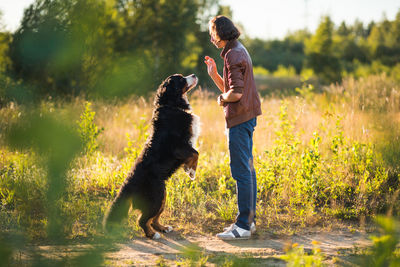 Full length of woman with dog on field