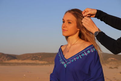 Young woman standing against clear blue sky