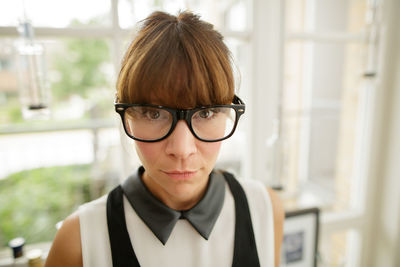 Close-up portrait of woman with bangs wearing eyeglasses at home
