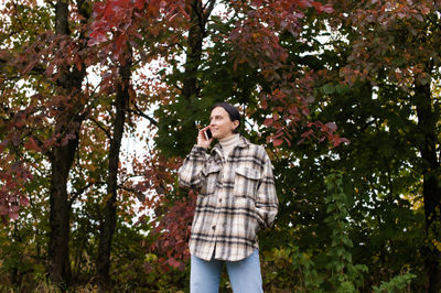 A cute girl has a pleasant conversation on the phone against the background of an autumn forest