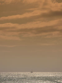 Distant ship on calm sea at sunset