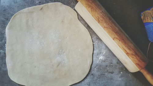 High angle view of dough by rolling pin on table