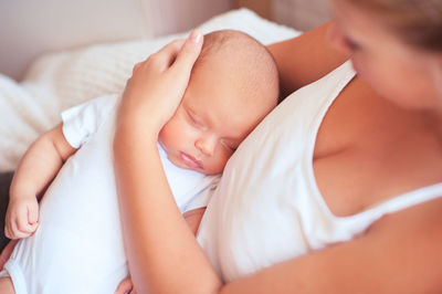 Mother holding sleeping baby at home