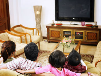 Rear view of family sitting on sofa at home