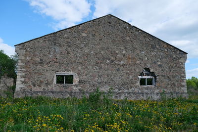 Exterior of old house on field against sky