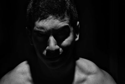 Close-up portrait of shirtless man against black background