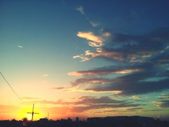 Low angle view of power lines against sky at sunset