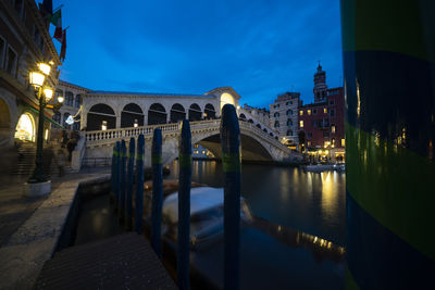 Bridge over river in city against blue sky at night